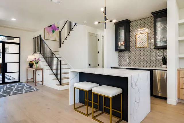 a kitchen with kitchen island granite countertop living room and white cabinets