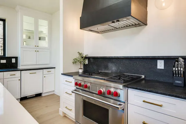 a kitchen with stainless steel appliances a stove and white cabinets