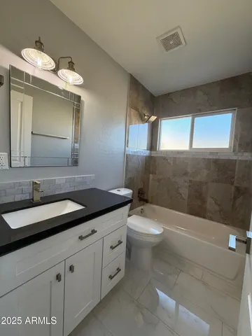 a bathroom with a granite countertop sink a toilet and mirror