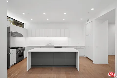 a view of counter top space with stainless steel appliances wooden floor and window