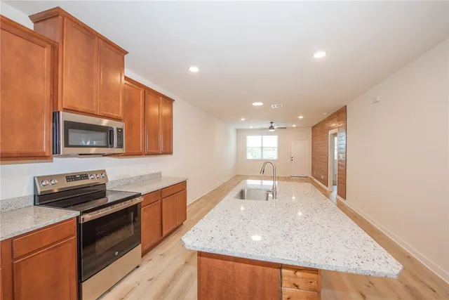 a large kitchen with stainless steel appliances granite countertop a sink a microwave counter space and wooden floor