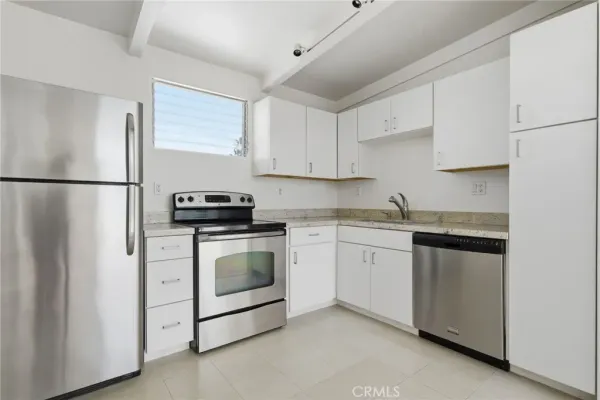a kitchen with white cabinets and refrigerator