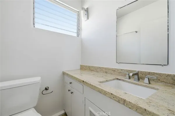 a bathroom with a granite countertop sink a mirror and a toilet