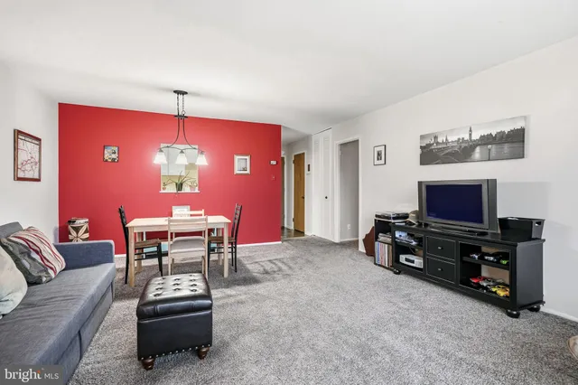 a living room with furniture a flat screen tv and a refrigerator