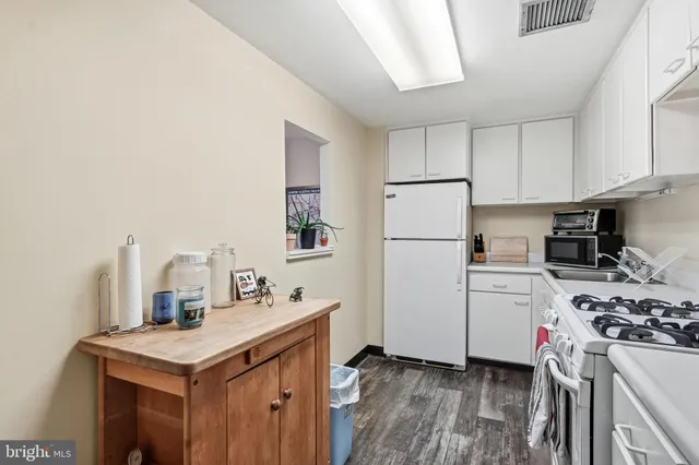 a kitchen with a sink a stove a refrigerator and white cabinets