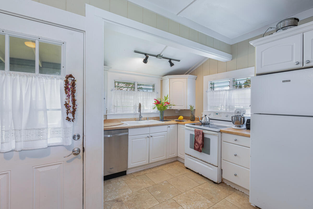 4463 Makaha Road Kapaa, HI 96746 - Photo 4 of 23 a kitchen with white cabinets and white appliances