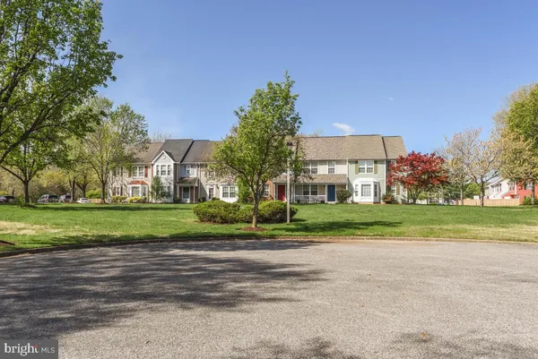 a front view of a house with a yard and large trees