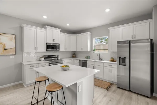 a kitchen with a refrigerator a stove cabinets and a sink