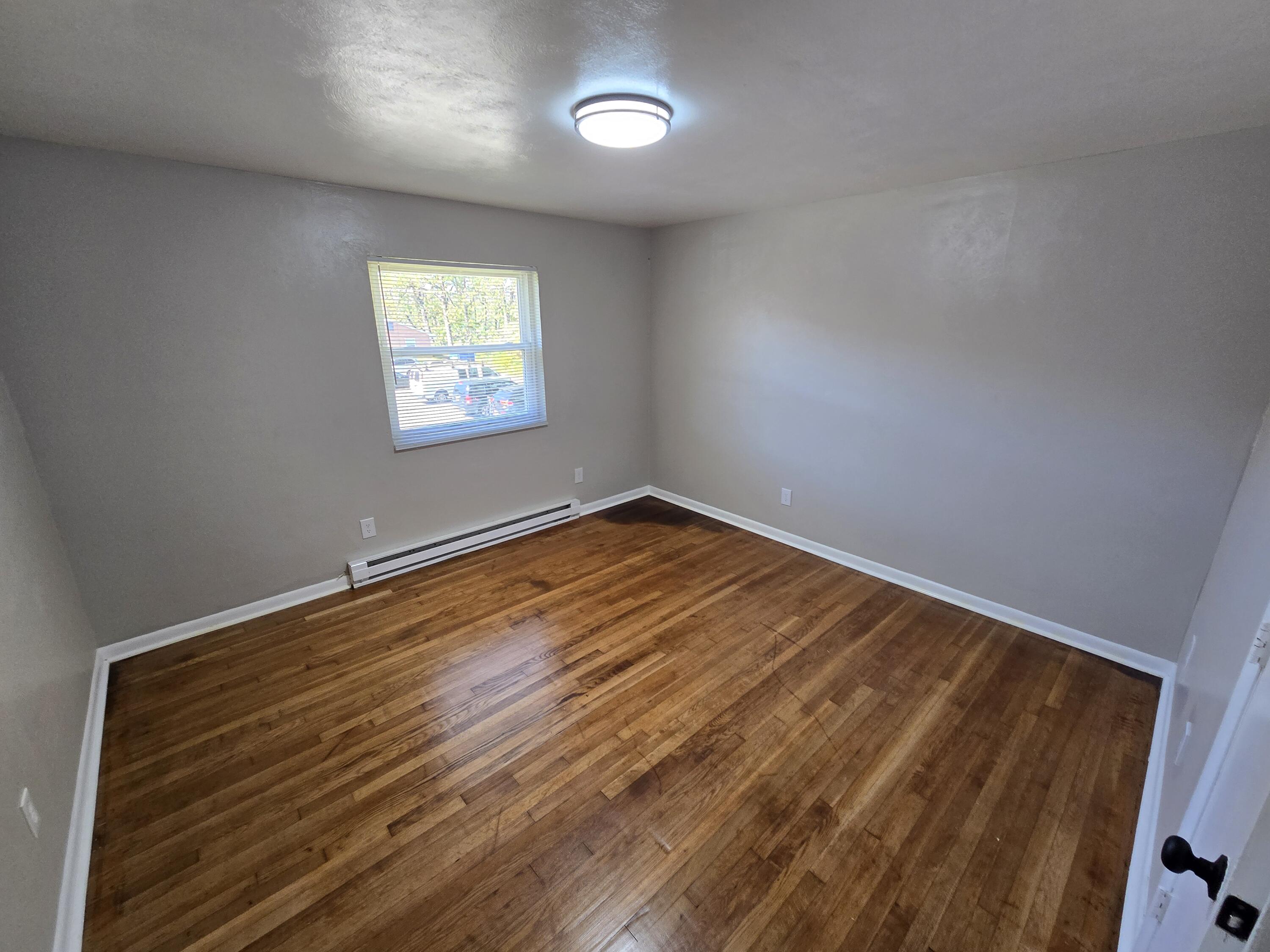 1301 Burks Street Southwest, Unit 204 Roanoke, VA 24015 - Photo 6 of 7 an empty room with wooden floor and windows