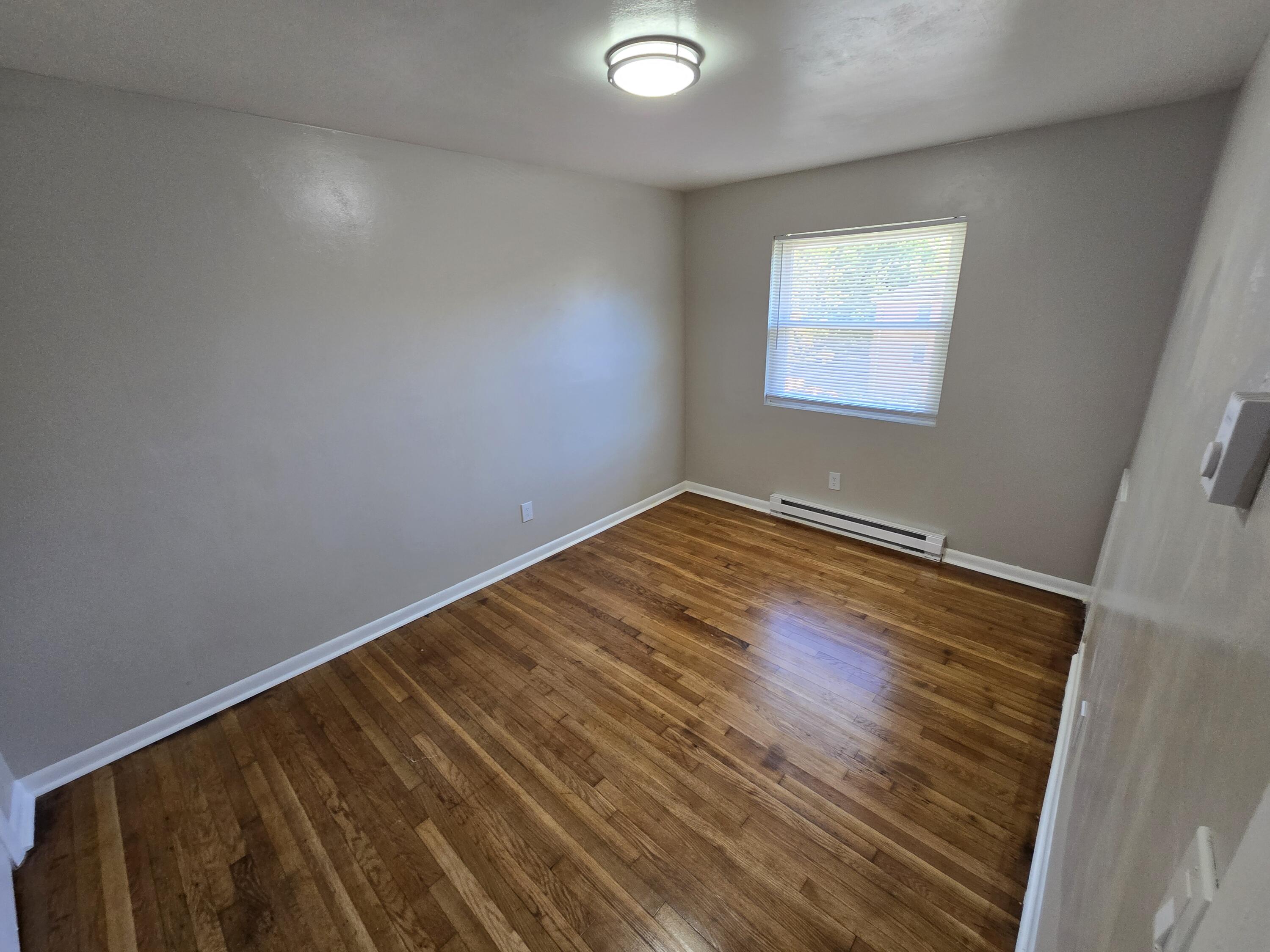 1301 Burks Street Southwest, Unit 204 Roanoke, VA 24015 - Photo 7 of 7 an empty room with wooden floor and windows