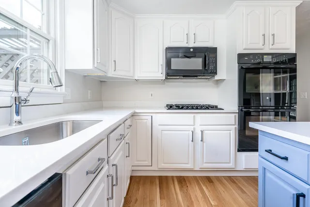 a kitchen with granite countertop white cabinets and stainless steel appliances