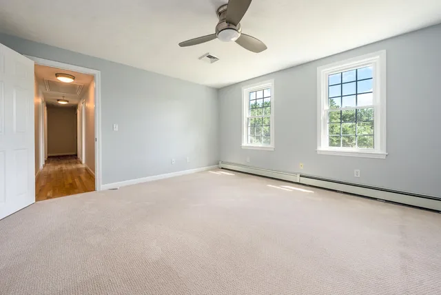 an empty room with windows and a ceiling fan