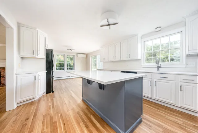 a kitchen with stainless steel appliances granite countertop a refrigerator a sink dishwasher a stove and white countertops with wooden floor