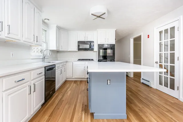 a kitchen with stainless steel appliances a sink dishwasher stove refrigerator and cabinets with wooden floor