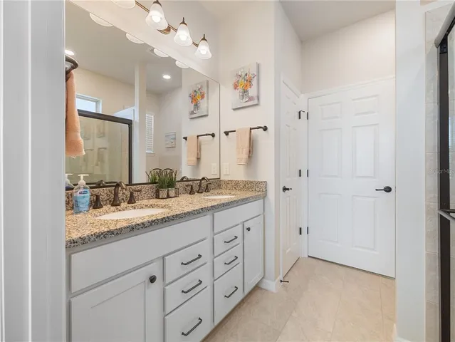 a bathroom with a granite countertop sink mirror and a shower