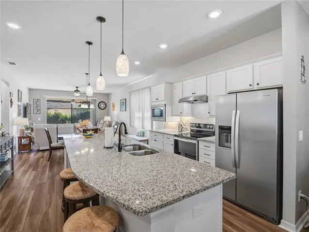 a kitchen with granite countertop kitchen island stainless steel appliances a refrigerator a stove a sink a dining table and chairs