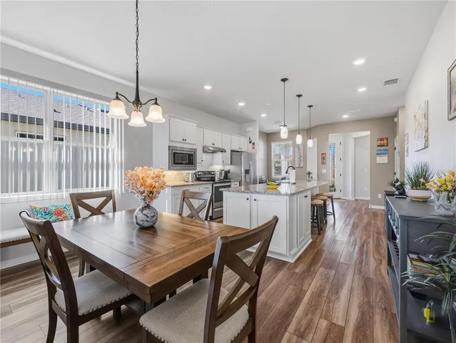 a view of a dining room and livingroom with furniture wooden floor kitchen chandelier