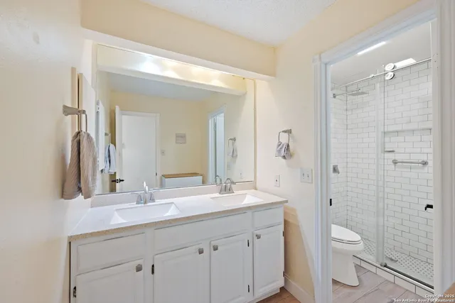 a bathroom with a granite countertop toilet a sink and a large mirror