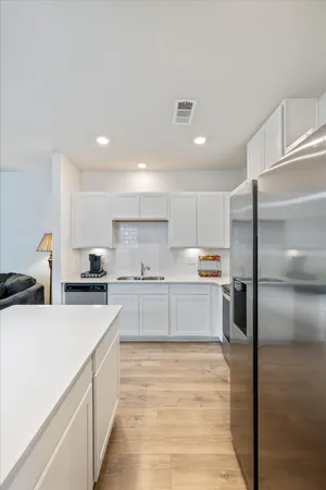 a kitchen with stainless steel appliances a refrigerator sink and white cabinets