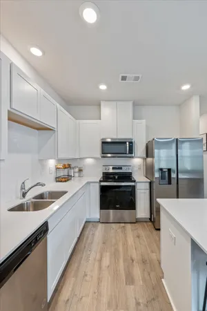 a kitchen with stainless steel appliances a sink a stove a refrigerator and cabinets
