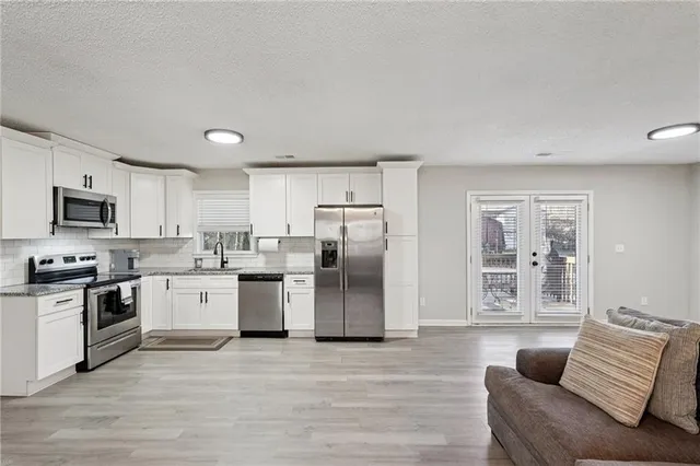 a kitchen with stainless steel appliances granite countertop a refrigerator stove top oven and sink