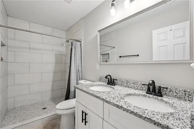 a bathroom with a granite countertop sink a toilet and shower
