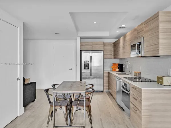 a kitchen with stainless steel appliances a table chairs refrigerator and cabinets