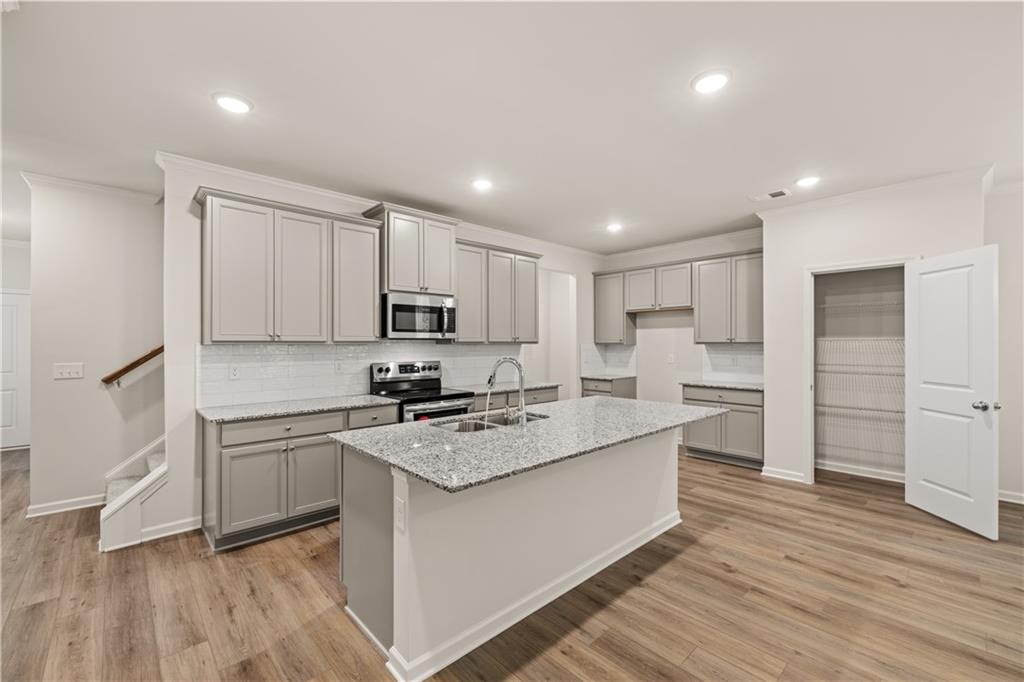 4516 Ajo Walk Atlanta, GA 30331 - Photo 5 of 13 a kitchen with stainless steel appliances granite countertop a stove a sink dishwasher a refrigerator and white cabinets with wooden floor