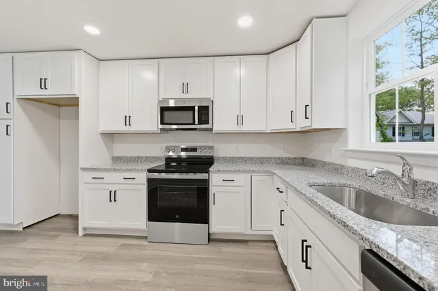 a kitchen with granite countertop white cabinets and stainless steel appliances