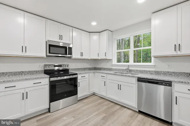 a kitchen with granite countertop white cabinets and appliances