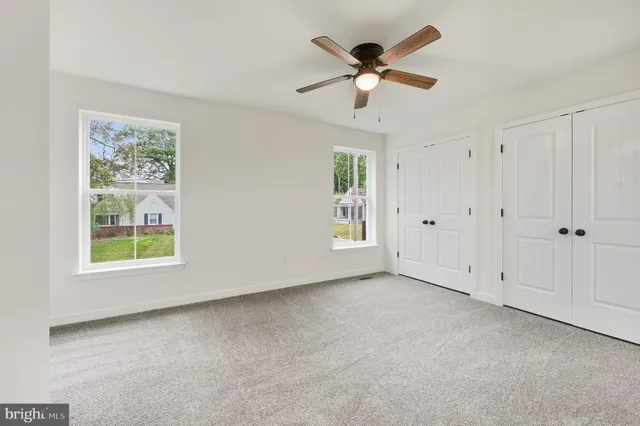 an empty room with windows and fan