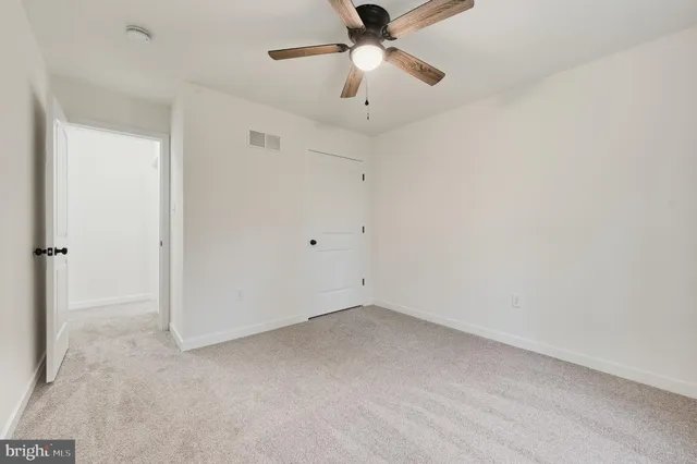 an empty room with ceiling fan and window