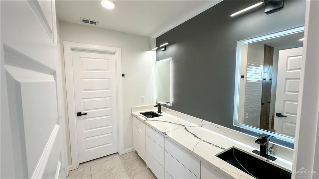 1509 Vida Dulce Weslaco, TX 78596 - Photo 13 of 24 a bathroom with a double vanity sink a mirror and a bathtub