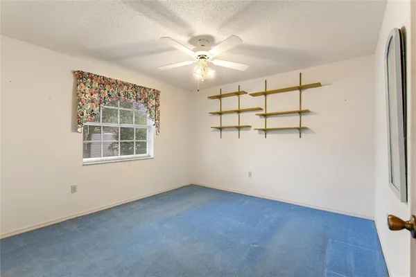 an empty room with windows and fan