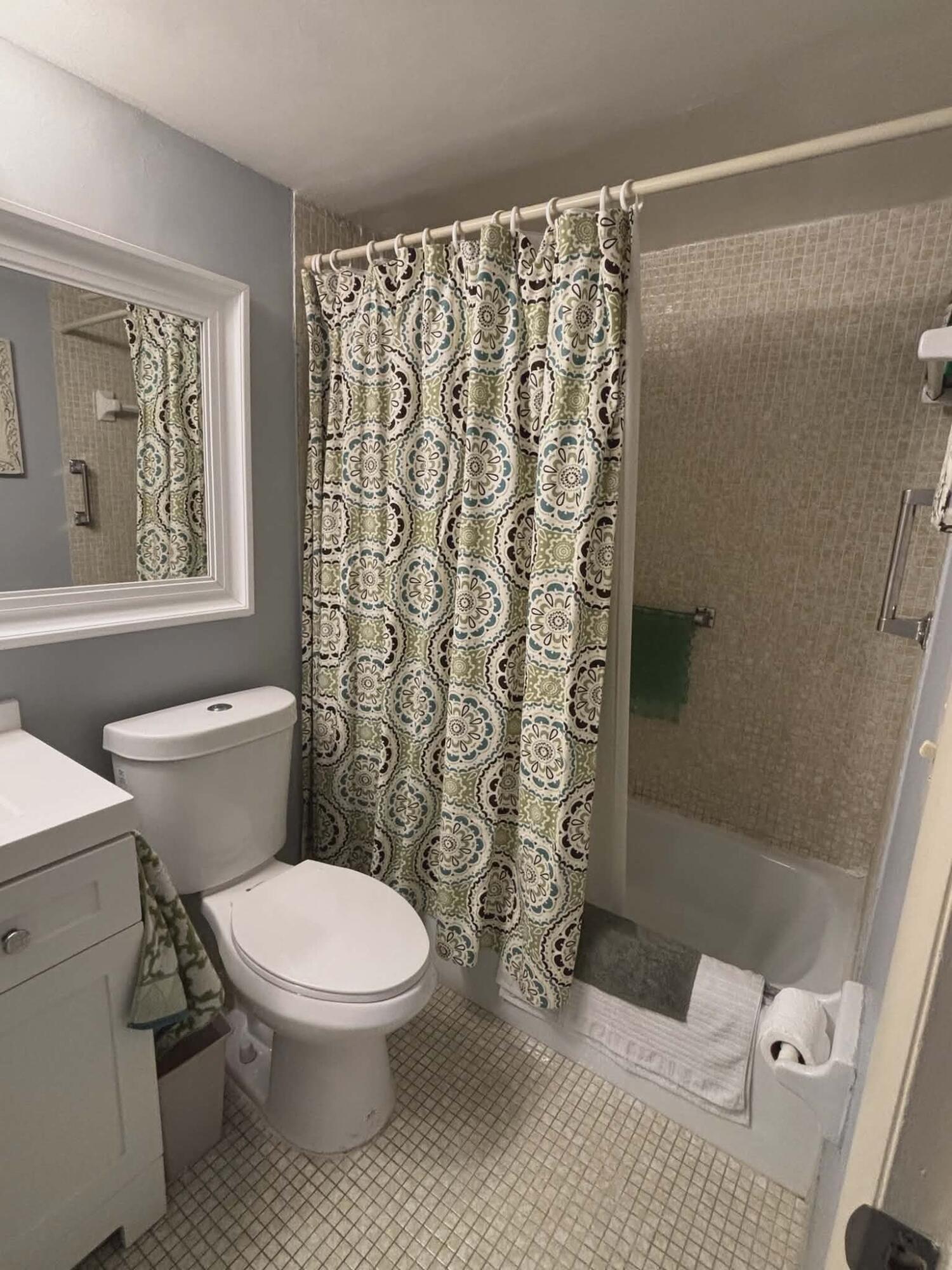 5550 North Ocean Boulevard, Unit 106 Ocean Ridge, FL 33435 - Photo 8 of 15 a white toilet sitting next to a shower curtain
