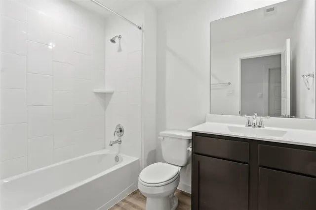 a bathroom with a toilet a sink a mirror a bathtub and vanity