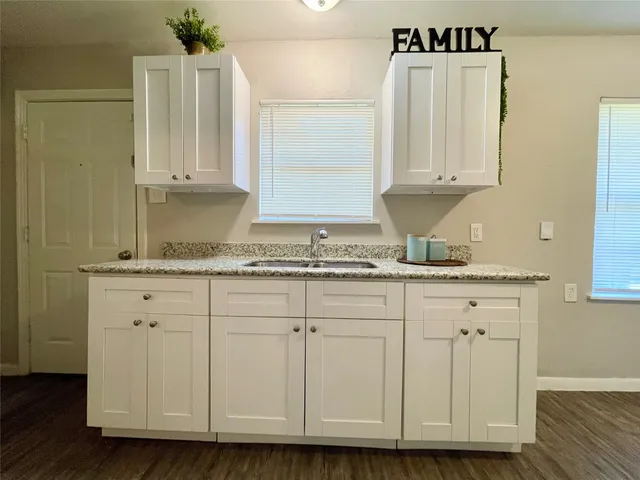 a kitchen with granite countertop white cabinets and sink
