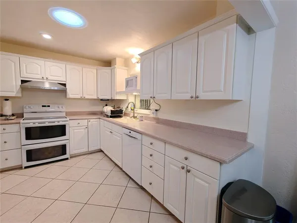 a kitchen with granite countertop white cabinets and white appliances