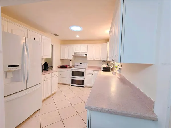 a kitchen with granite countertop a refrigerator sink stove and cabinets