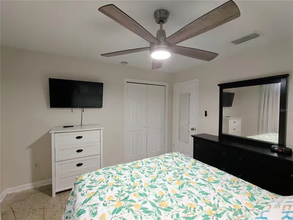 a bedroom with a bed and a flat tv screen on dresser