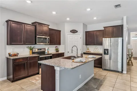 a kitchen with stainless steel appliances granite countertop a sink stove refrigerator and cabinets