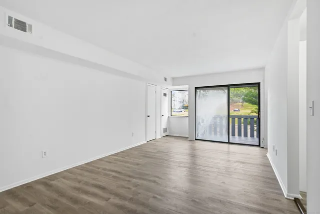 an empty room with wooden floor and windows