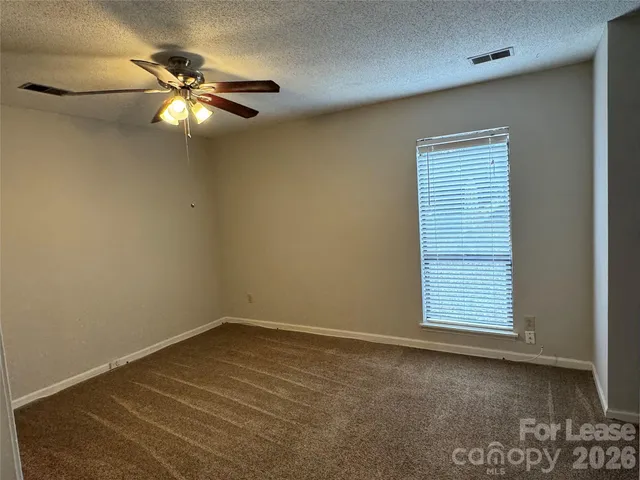 an empty room with closet and a chandelier fan