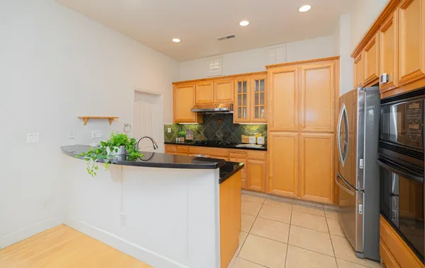 a kitchen with stainless steel appliances granite countertop a refrigerator a sink and a stove