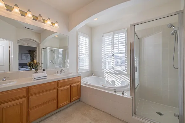 a bathroom with a granite countertop sink a mirror a bathtub and shower