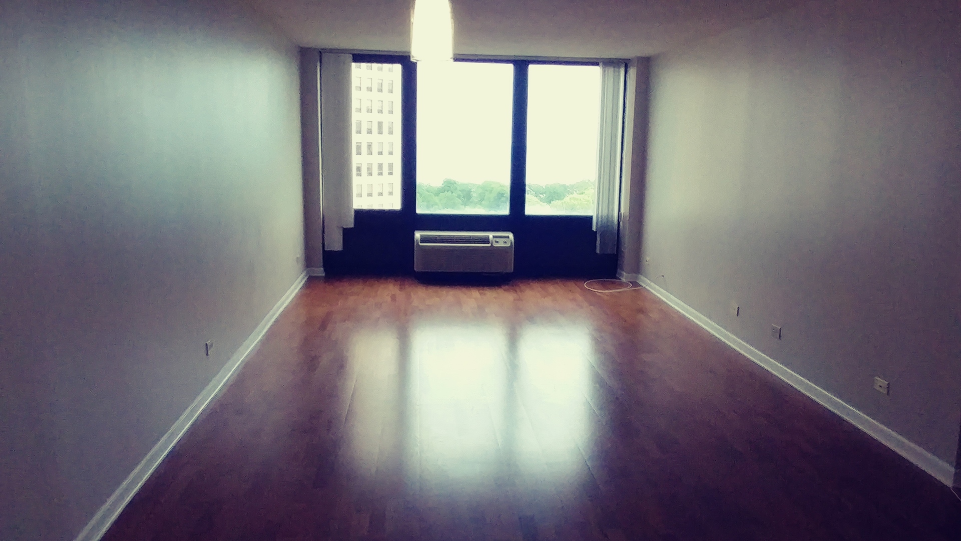 5320 North Sheridan Road, Unit 1207 Chicago, IL 60640 - Photo 11 of 20 an empty room with wooden floor and windows