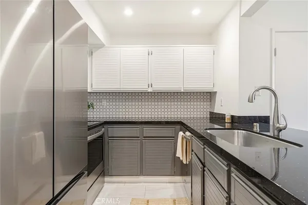 a kitchen with granite countertop a sink and a refrigerator