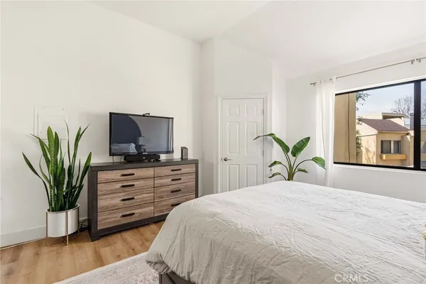 a bedroom with a bed potted plant on the dresser and a flat screen tv