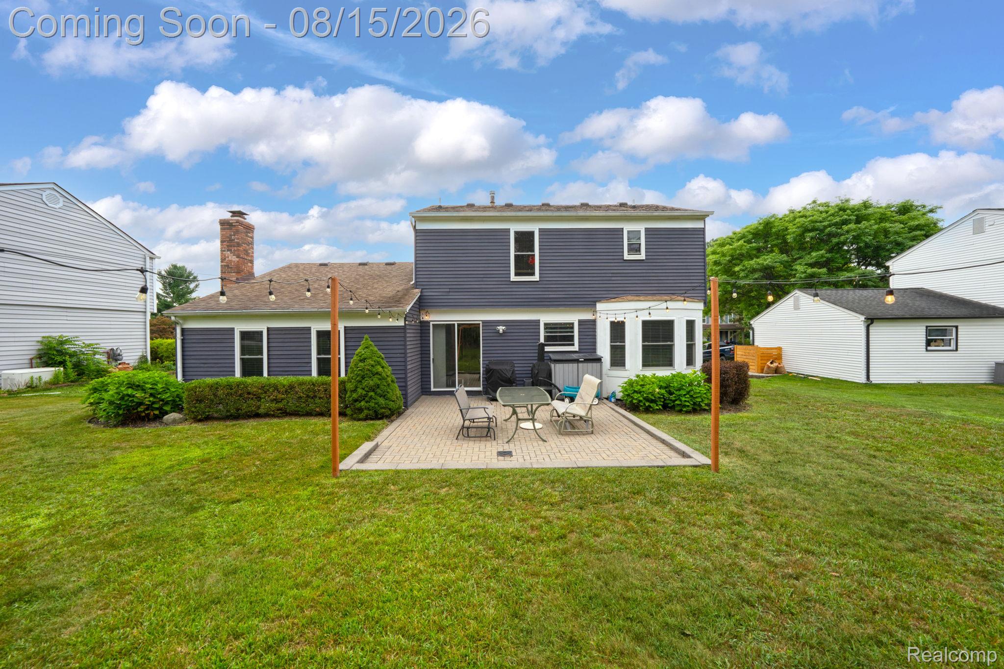 385 Arlington Drive Rochester, MI 48307 - Photo 14 of 47 Rear exterior with dark blue siding, brick chimney, and a paver patio