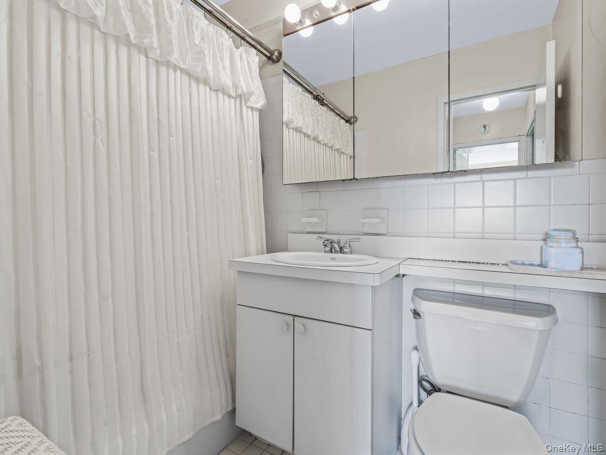 77 Fulton Street, Unit 19C Manhattan, NY 10038 - Photo 18 of 20 a bathroom with a sink a toilet and vanity
